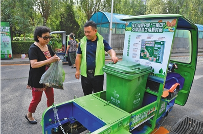 2019年7月24日上午，朝阳区甜水西园社区居民向垃圾分类回收车内投放垃圾，志愿者在一边协助指导。