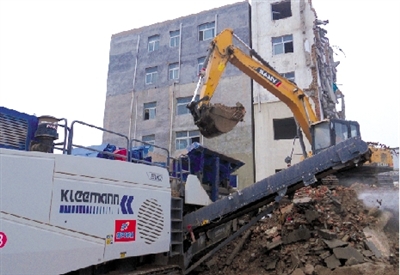 挖掘机向可移动式破碎机喂料槽填送大块建筑垃圾