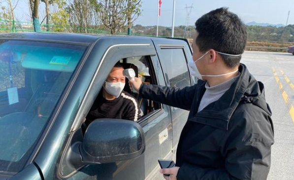 工作人员正为进出人员测量体温