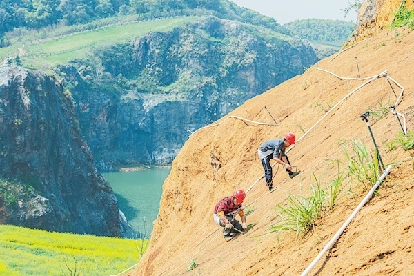 3月28日，武汉市江夏区灵山生态文化旅游区“矿花苑”景区一期，施工人员在覆土的山体上种植树种。